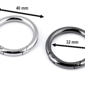 May include: Two metal key rings, one silver and one black. The silver ring is 40 mm in diameter and the black ring is 32 mm in diameter.