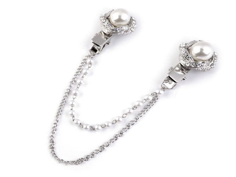 May include: A silver chain with two pearl and rhinestone accents. The chain has two clasps, one on each end.