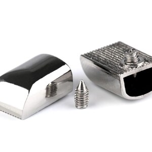 May include: Three silver metal pieces, including a small screw, a curved piece with a textured edge, and a rectangular piece with a textured top and a hollowed-out section.