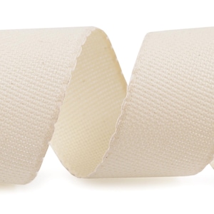 May include: A close-up of a cream-coloured cotton ribbon, showing the woven texture of the fabric.