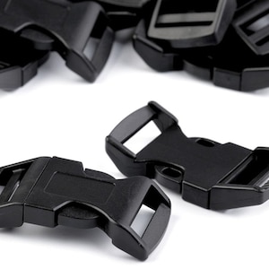 Può includere: Fibbie di rilascio laterale in plastica nera. Le fibbie sono progettate per essere utilizzate con cinghie o nastri. Hanno una finitura liscia e opaca.