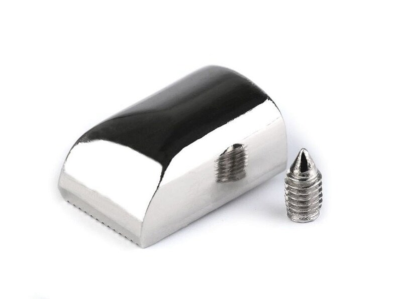 May include: A silver metal tool with a rounded, grooved head and a pointed tip. The tool is used for making holes in leather or other materials.