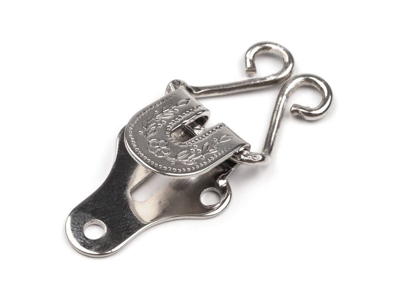 May include: Silver metal hook and eye closure with a floral design. The hook has two loops and the eye has a decorative floral pattern.