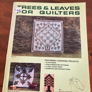 May include: A light green instructional book titled Trees & Leaves for Quilters by Betty Boyink. The cover features photographs of quilts with tree motifs, text detailing 52 patterns, 4-inch miniature patterns, and 8- and 12-inch sizes.