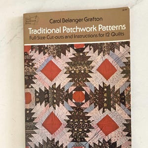 May include: A book titled "Traditional Patchwork Patterns" by Carol Belanger Grafton. The cover features a quilt design with red, brown, and blue geometric shapes. The book includes full-size cut-outs and instructions for 12 quilts. The Dover Needlework Series logo is visible.