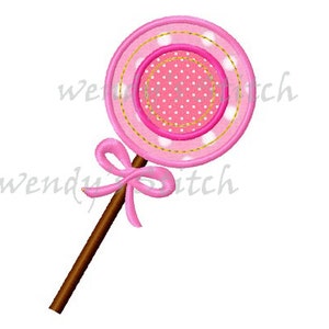 May include: A pink and white lollipop with a brown stick and a pink bow. The lollipop has a white center with pink polka dots and a pink outer ring with white polka dots.