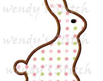 May include: A brown outline of a sitting bunny with pink and green polka dots on a white background.