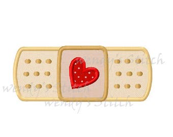 Puede incluir: Un parche bordado con forma de vendaje, en beige y marrón, con un corazón rojo con lunares blancos en el centro.