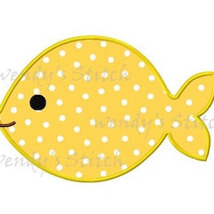 May include: A yellow fish with white polka dots and a black eye. The fish has a small, curved mouth and a tail fin.