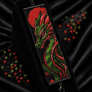 May include: A rectangular beaded bracelet featuring a dragon design in green, red, and black. The text reads Bracelet Bead Pattern, PDF, Instant Download, Loom Stitch, Miyuki Delica 11/0, Color Chart, and Word Chart. The bracelet has a metal clasp.