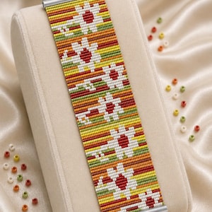 May include: A beaded bracelet pattern with a floral design, featuring red, white, yellow, green, and orange beads. The bracelet is displayed on a beige surface. Text at the top reads "Bracelet Bead Pattern". The bottom text says "LOOM STITCH".