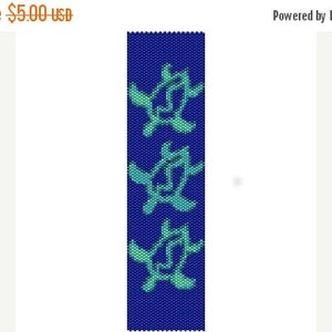 Könnte beinhalten: Ein Armband aus Perlen mit einem sich wiederholenden Muster aus drei türkisfarbenen Meeresschildkröten auf dunkelblauem Hintergrund.