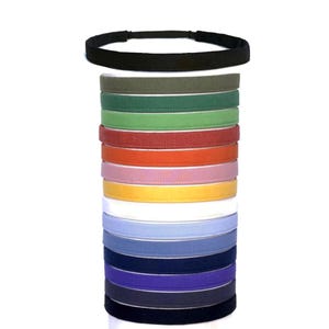 May include: A stack of colorful headbands in various shades, including black, green, red, orange, pink, yellow, white, blue, navy, and purple. The headbands are made of a soft material and are designed to be worn around the head.