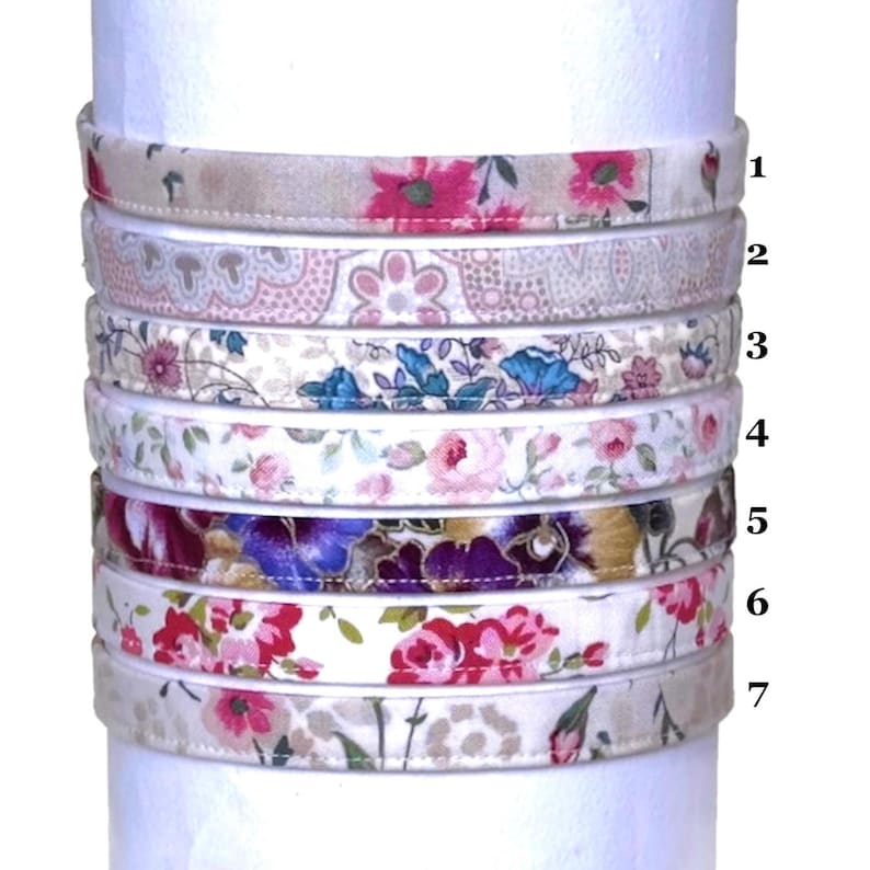 May include: Seven different fabric headbands with floral patterns in various colors, including pink, blue, purple, and white. The headbands are stacked on top of each other, with the numbers 1 through 7 next to them.