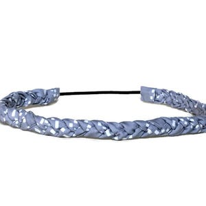 May include: A braided headband featuring a light blue fabric with a repeating white square pattern. The braided section is connected by a thin, black elastic band at the back, creating a circular shape for the hair accessory.