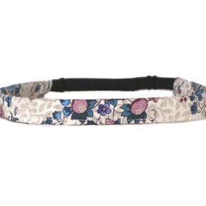 May include: A thin, stretchy headband with a floral print. The headband is cream colored with pink, blue, and green flowers and leaves.