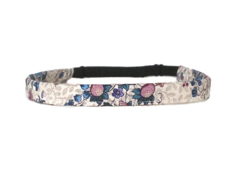 May include: A thin, stretchy headband with a floral print. The headband is cream colored with pink, blue, and green flowers and leaves.
