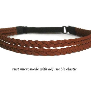 May include: A rust-colored microsuede headband with a braided design. The headband features an adjustable black elastic band for a comfortable fit. The text "rust microsuede with adjustable elastic" is visible.