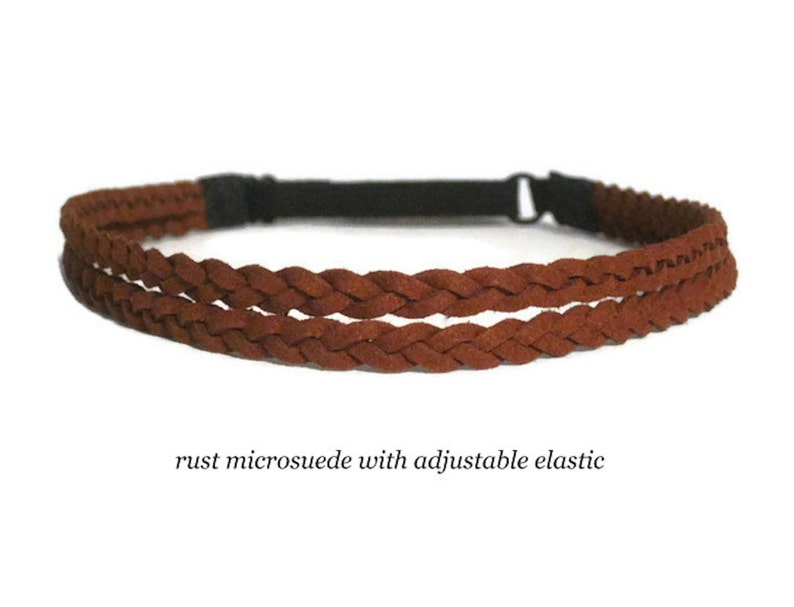 May include: A rust-colored microsuede headband with a braided design. The headband features an adjustable black elastic band for a comfortable fit. The text "rust microsuede with adjustable elastic" is visible.