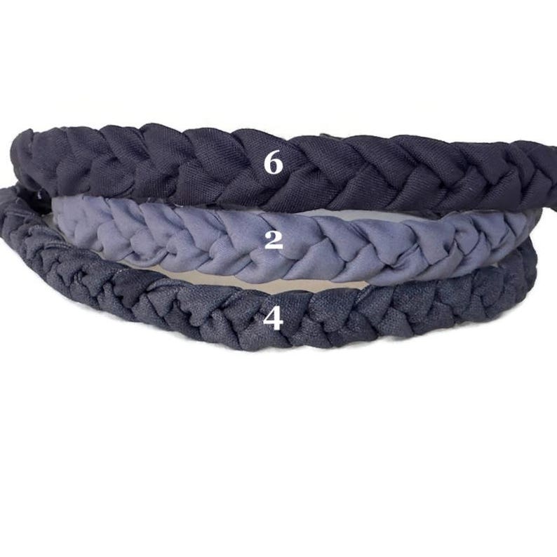 May include: Three braided headbands stacked vertically. The top headband is dark charcoal gray with the number 6, the middle is light slate blue with the number 2, and the bottom is dark navy blue with the number 4 printed in white on each.