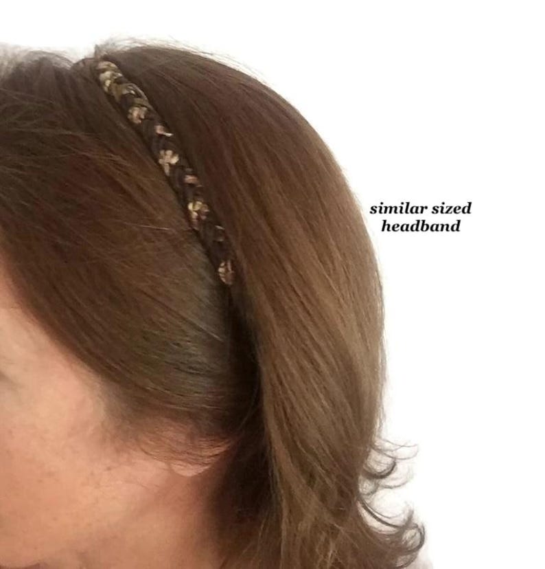 May include: A thin, braided headband featuring a dark brown base with interwoven light brown and tan accents. The accessory is positioned on brown hair, with text to the right reading similar sized headband, indicating the scale of the item.