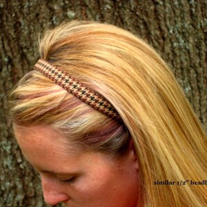 May include: A brown and black patterned headband worn by a person with long blonde hair. The headband is about 1/2 inch wide.