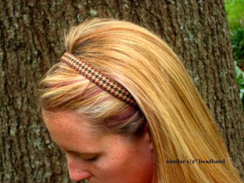 May include: A brown and black patterned headband worn by a person with long blonde hair. The headband is about 1/2 inch wide.