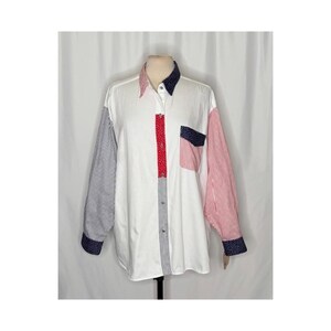 May include: A long-sleeve button-down shirt featuring a white base with a patchwork design. The left sleeve has blue and white pinstripes, while the right sleeve has red and white pinstripes. It includes a red polka dot placket and a chest pocket.