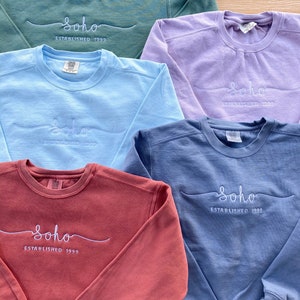May include: Five different coloured sweatshirts with the text "Soho Established 1999" embroidered on the front in white. The sweatshirts are in the colours green, purple, light blue, blue, and red.