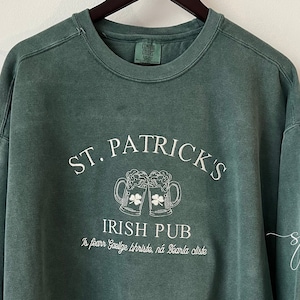 Sudadera de cuello redondo bordada con el logo de St. Patrick's Irish Pub, letras de imprenta de inspiración vintage, colores azul universitario, verde abeto y confort Irish