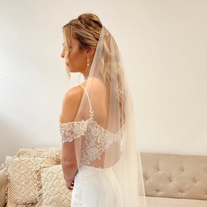 Bride is wearing a very fine, sheer veil. It is mid length which goes to the knees. It is made from fine quality tulle which is very soft to the touch. The veil is very sheer and allows the back details of the wedding dress to show through.