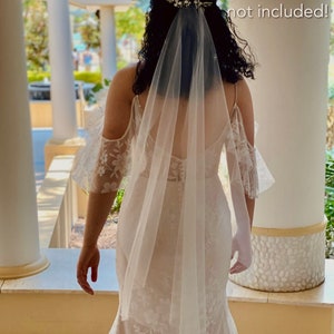 Bride is wearing a very fine, sheer veil. It is mid length which goes to the knees. It is made from fine quality tulle which is very soft to the touch. The veil is very sheer and allows the back details of the wedding dress to show through.