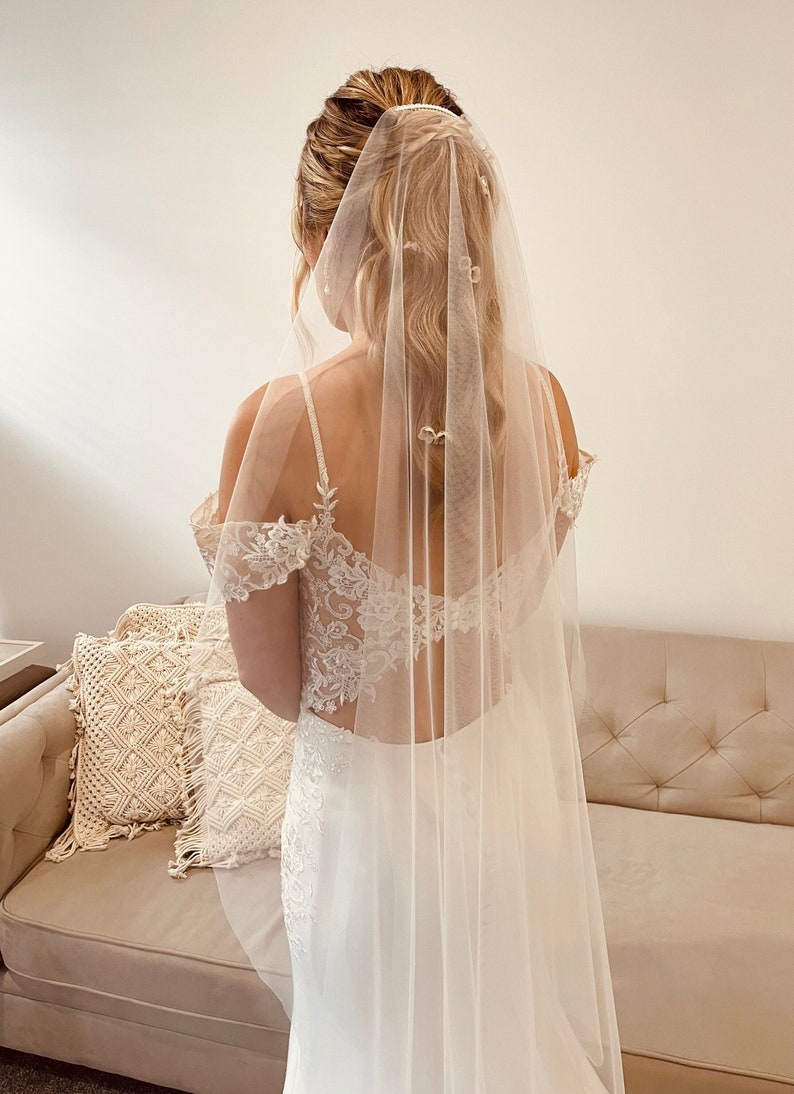 Bride is wearing a very fine, sheer veil. It is mid length which goes to the knees. It is made from fine quality tulle which is very soft to the touch. The veil is very sheer and allows the back details of the wedding dress to show through.
