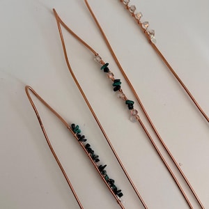 May include: Four copper hair pins with decorative bead accents. Each pin features a different arrangement of beads, including clear crystals, pink beads, and dark green stones. The pins are arranged diagonally against a white background.