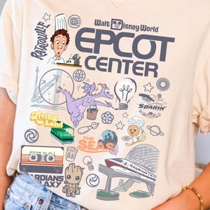Puede incluir: Camiseta de color marfil con un diseño gráfico del logotipo del Centro EPCOT y varias ilustraciones temáticas de Disney. El diseño incluye personajes e iconos del parque temático. La camiseta se combina con pantalones cortos vaqueros.