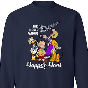 May include: A navy blue sweatshirt with a white graphic of Mickey Mouse, Donald Duck, Goofy, and Pluto playing music. The text "The World Famous Dapper Dans" is printed below the graphic.