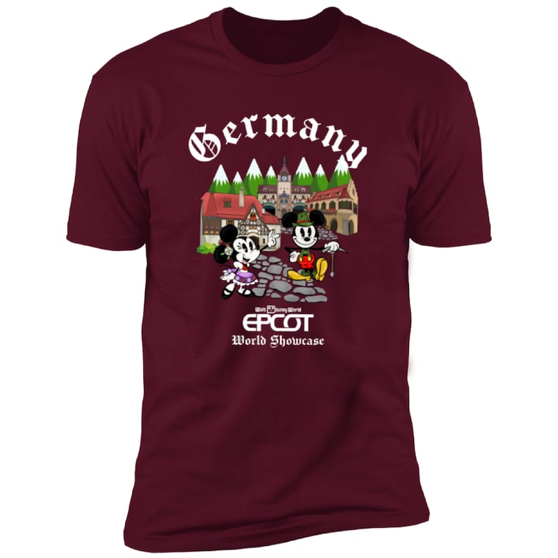 May include: A maroon t-shirt with a white graphic of Mickey and Minnie Mouse in front of a German village. The text "Germany" is above the image and "Walt Disney World EPCOT World Showcase" is below the image.