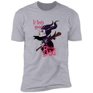 Puede incluir: Una camiseta gris jaspeada con una imagen de dibujos animados de Mal&eacute;fica de La Bella Durmiente de Disney. El texto "It feels good... to be Bad" est&aacute; impreso en la camiseta en rosa.