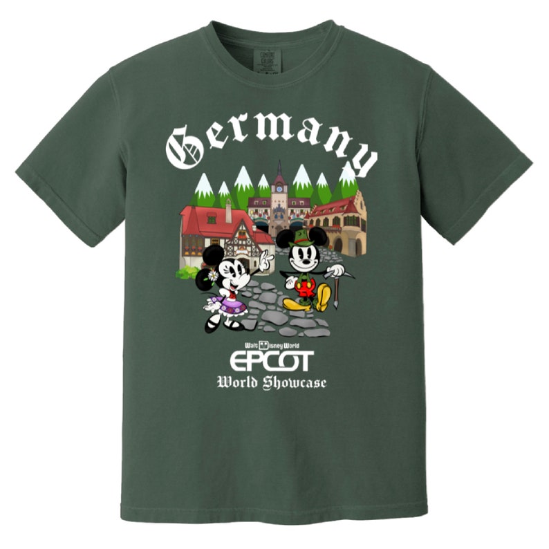 May include: A green t-shirt with a white graphic of Mickey and Minnie Mouse in German attire in front of a German village. The text "Germany" is above the image and "Walt Disney World EPCOT World Showcase" is below the image.