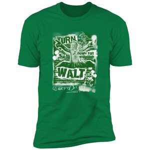 Puede incluir: Una camiseta verde con un estampado gr&aacute;fico blanco de Walt Disney con el texto "Turn Down For Walt" y "Warped Disney" en estilo graffiti.