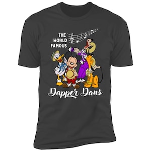 May include: A dark gray t-shirt with a white graphic of Mickey Mouse, Donald Duck, Goofy, and Pluto playing music. The text "The World Famous Dapper Dans" is printed below the graphic.