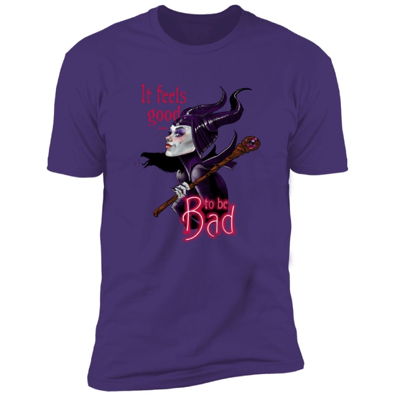 Puede incluir: Camiseta morada con una imagen de dibujos animados de Mal&eacute;fica de La Bella Durmiente de Disney. El texto "It feels good to be bad" est&aacute; impreso en rojo en la camiseta.