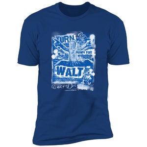 Puede incluir: Una camiseta azul con un estampado gr&aacute;fico blanco de Walt Disney en un estilo de p&oacute;ster vintage. El p&oacute;ster presenta el texto "Turn Down For Walt" y una firma en la parte inferior.