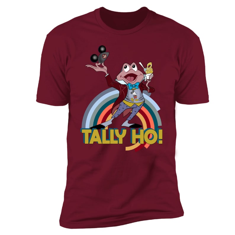 May include: Burgundy t-shirt with a cartoon frog in a red coat, holding a Mickey Mouse ice cream and a Mickey Mouse ear hat. The shirt has a rainbow design and the text "TALLY HO!"