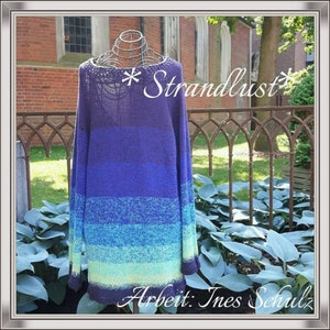 Puede incluir: Un suéter de punto a rayas azul, verde y morado con una etiqueta *Strandlust*. El suéter está en un maniquí frente a una pared de ladrillo y una valla de hierro forjado.