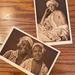 May include: Two vintage black and white postcards featuring portraits of young people. The first postcard shows a young man wearing a turban and traditional clothing. The second postcard shows two young people, one with dark skin and the other with light skin, both wearing turbans and traditional clothing. The text on the second postcard reads "Les bons amis".