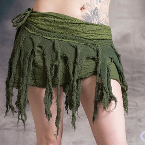 Green skirt with frayed edges and a tie closure. The skirt is made of a soft, lightweight fabric and has a flowy, bohemian style.