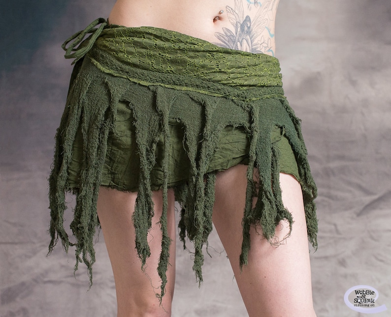 Green skirt with frayed edges and a tie closure. The skirt is made of a soft, lightweight fabric and has a flowy, bohemian style.