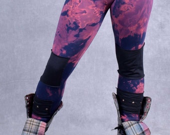May include: Black leggings with a red and blue tie-dye pattern and black knee patches. The leggings are paired with black combat boots with plaid fabric accents.