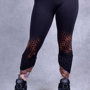 May include: Black leggings with a geometric pattern on the lower legs. The pattern is a copper color and resembles a flower of life design. The leggings are made of a stretchy fabric and have a comfortable fit.